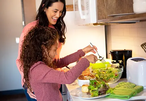 A mom and her child making salad in their hotel room